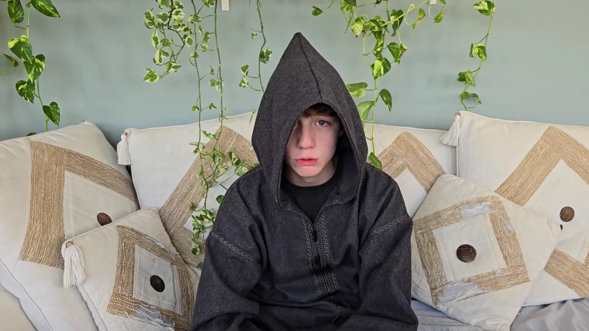 Eesa Fox in a hooded grey robe sitting on a sofa